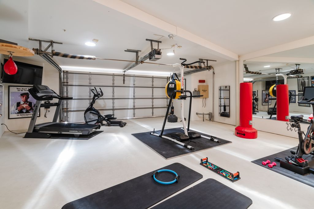 The garage gym is filled with treadmills, stationary bikes, punching bags, and functional fitness equipment.