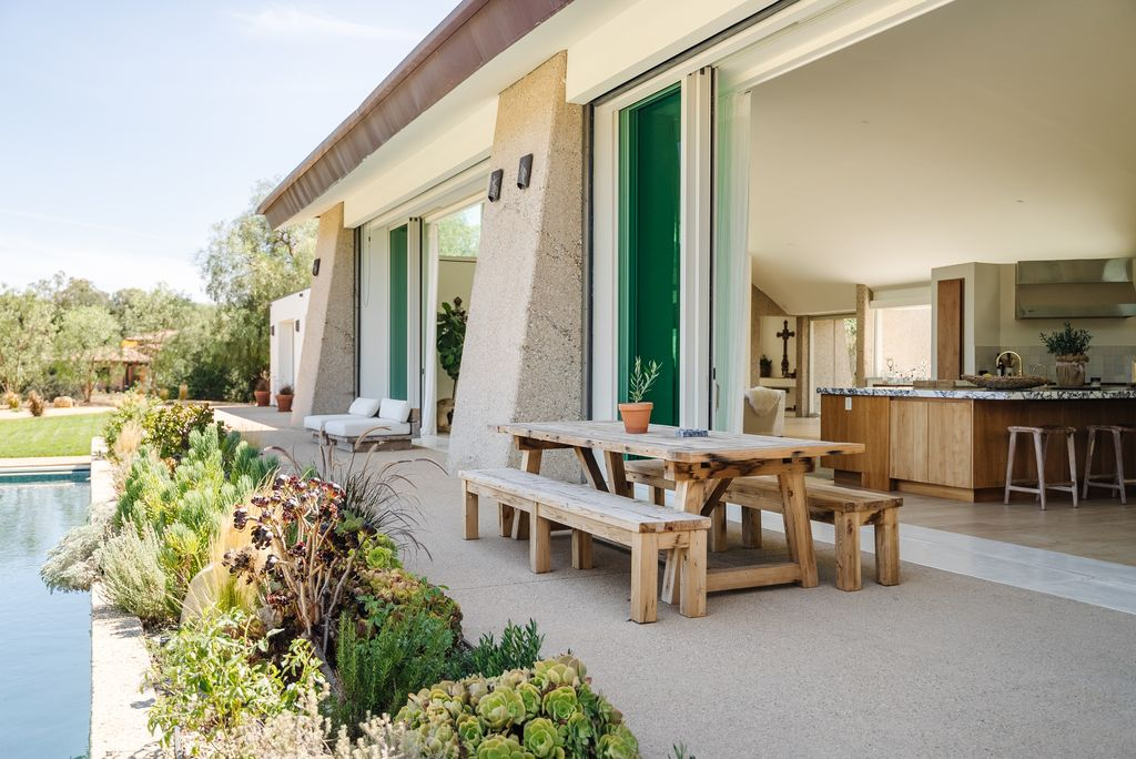 Sliding glass walls open completely to this area, allowing the marble kitchen island and outdoor picnic-style table to feel connected.