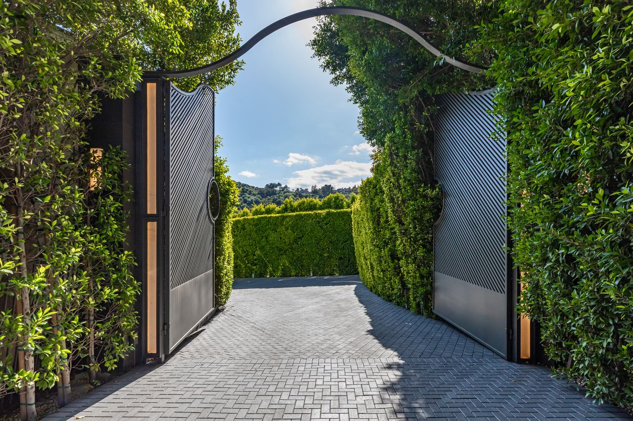 Gated entrance surrounded by tall green hedges.