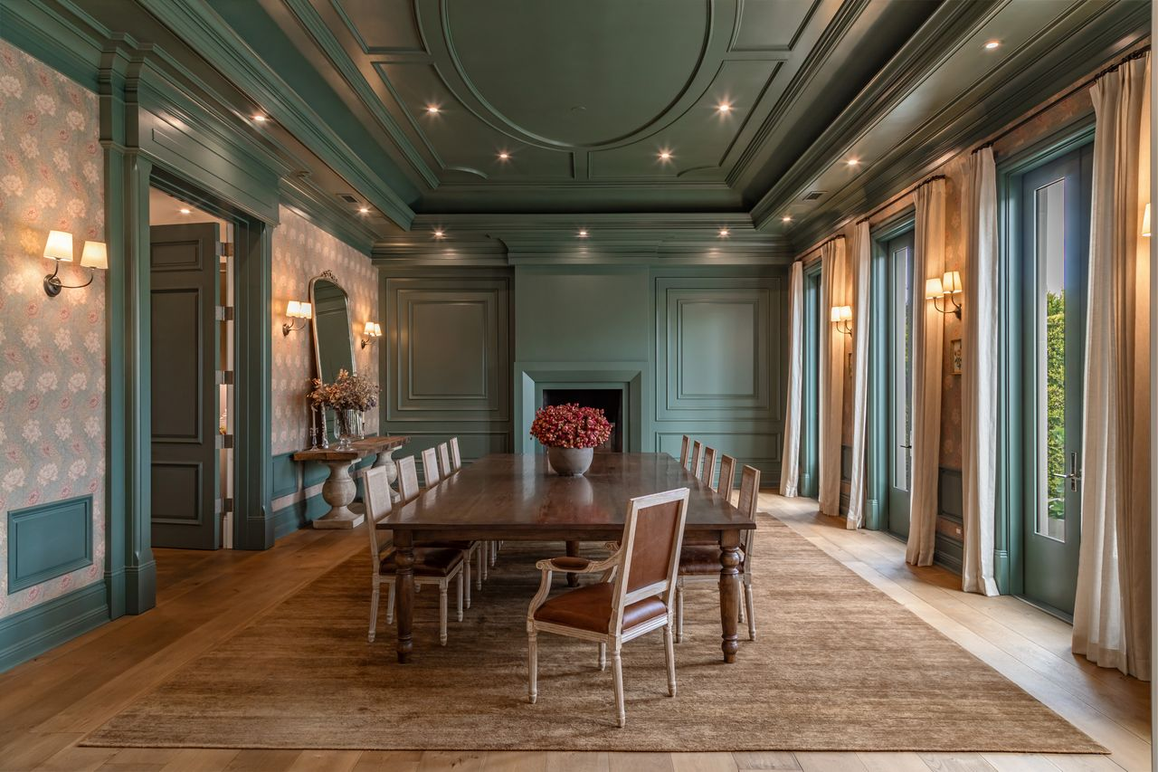 The formal dining room features deep green millwork that wraps across the walls and ceiling, with detailed paneling and a dramatic oval ceiling treatment.