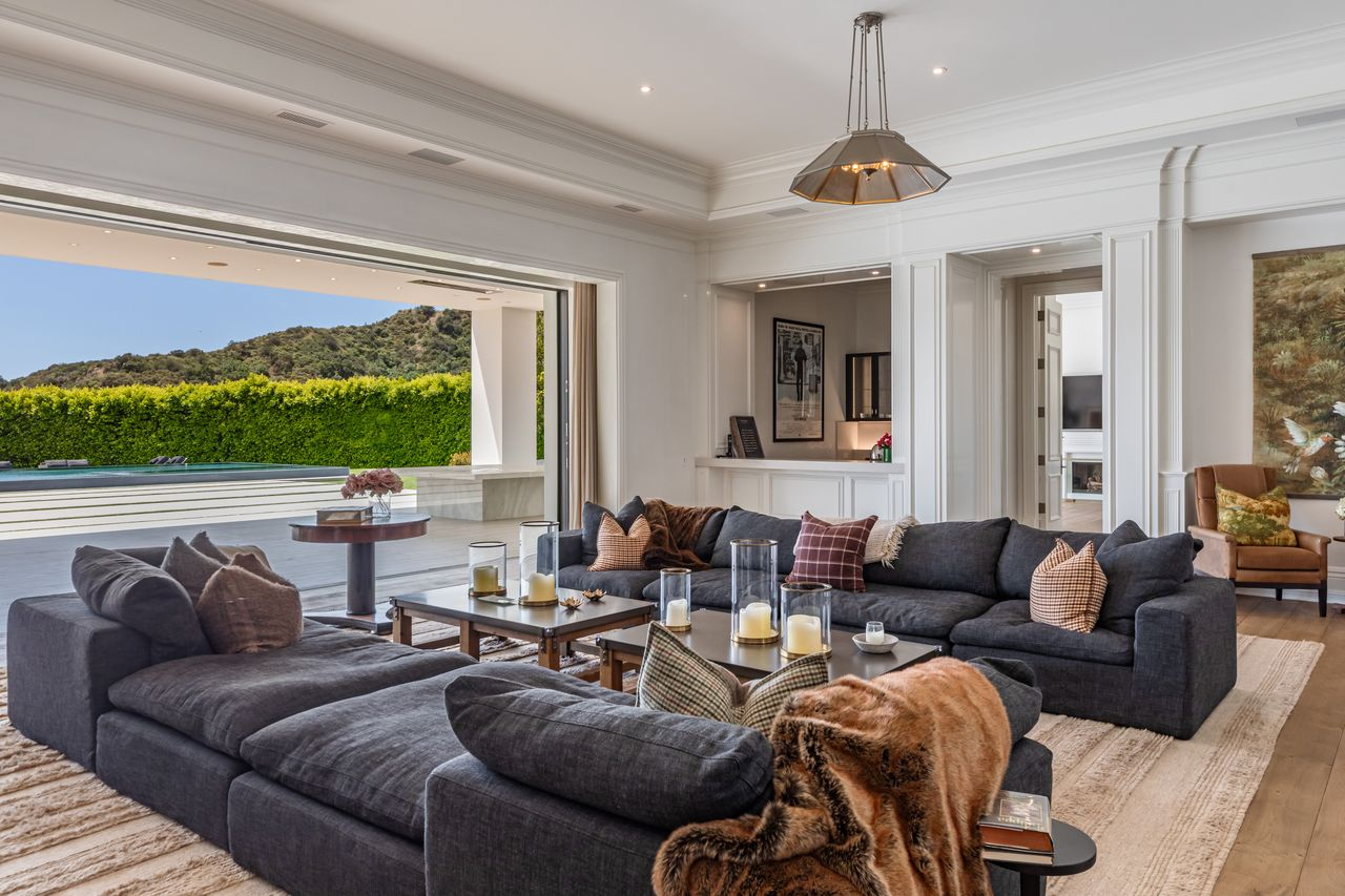 The spacious layout accommodates two large plush sofas, multiple coffee tables, and an intimate corner bar perfect for entertaining.