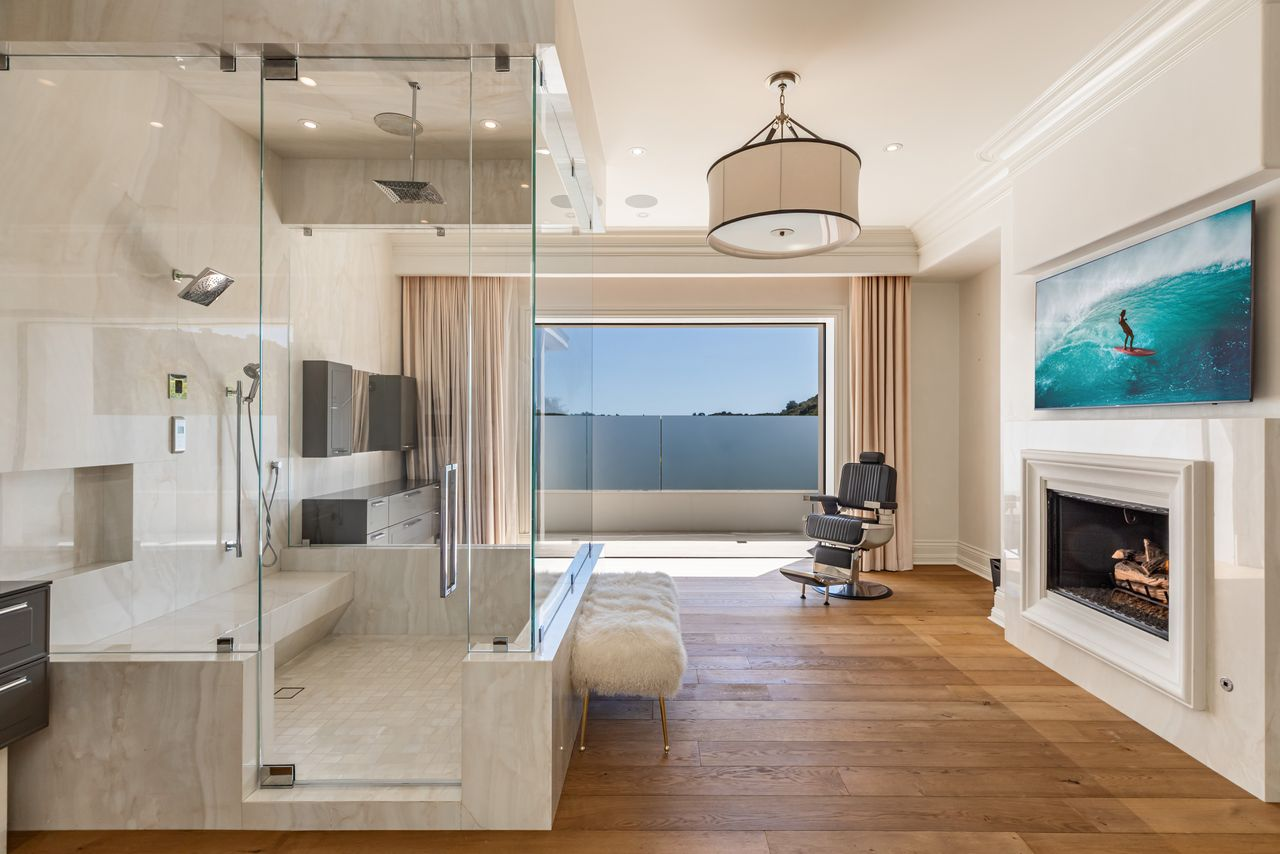 The second bathroom continues the same palette but with a more streamlined layout focused around the expansive glass shower enclosure.