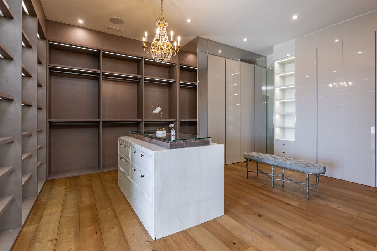 Separate walk-in closets accompany each bathroom, both designed with custom built-ins, illuminated shelving, and central storage islands. 