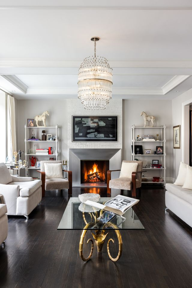 The layout is arranged around a modern fireplace with built-in shelving on either side, balancing contemporary furnishings with the apartment’s original prewar proportions. 