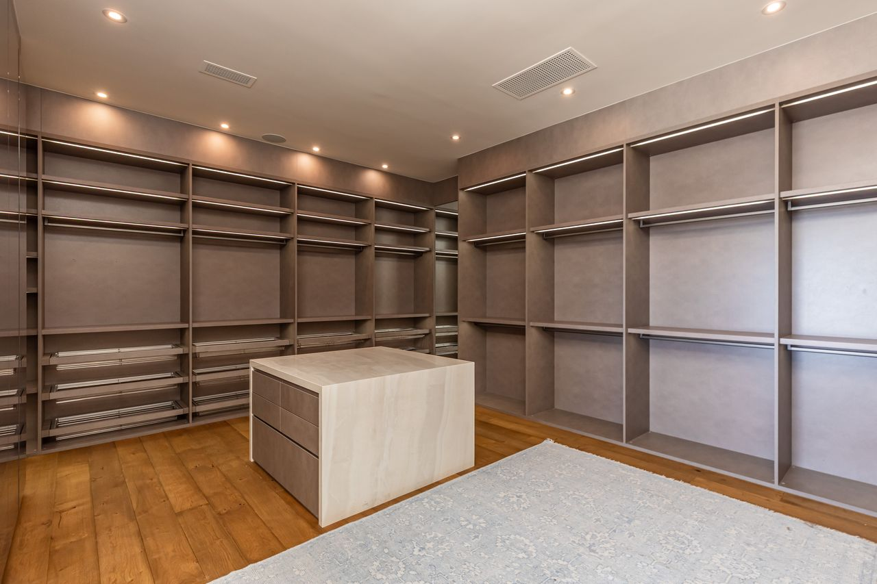 Closet with lighter finishes and a stone-topped island at the center.