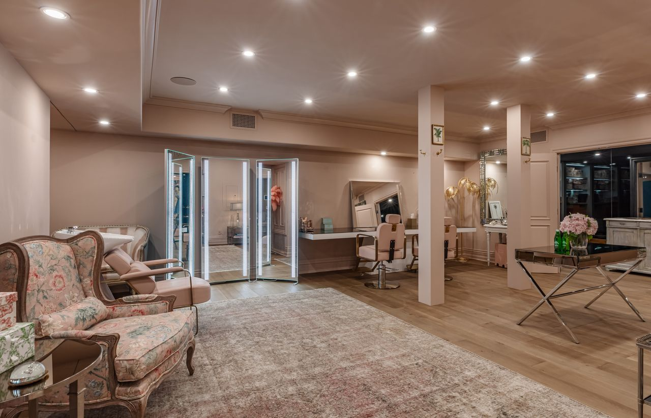 The salon is designed as a full beauty and prep space with multiple styling stations, mirrored vanities, and dedicated wash areas spread throughout the open layout. 