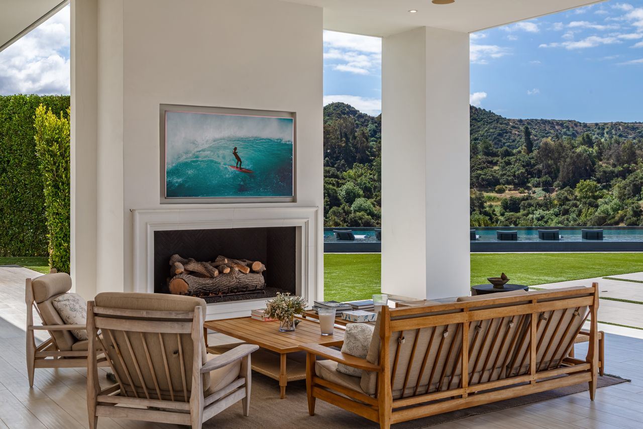 Just outside the main living areas, the covered lounge creates an outdoor extension of the home with oversized seating arranged around a built-in fireplace. 