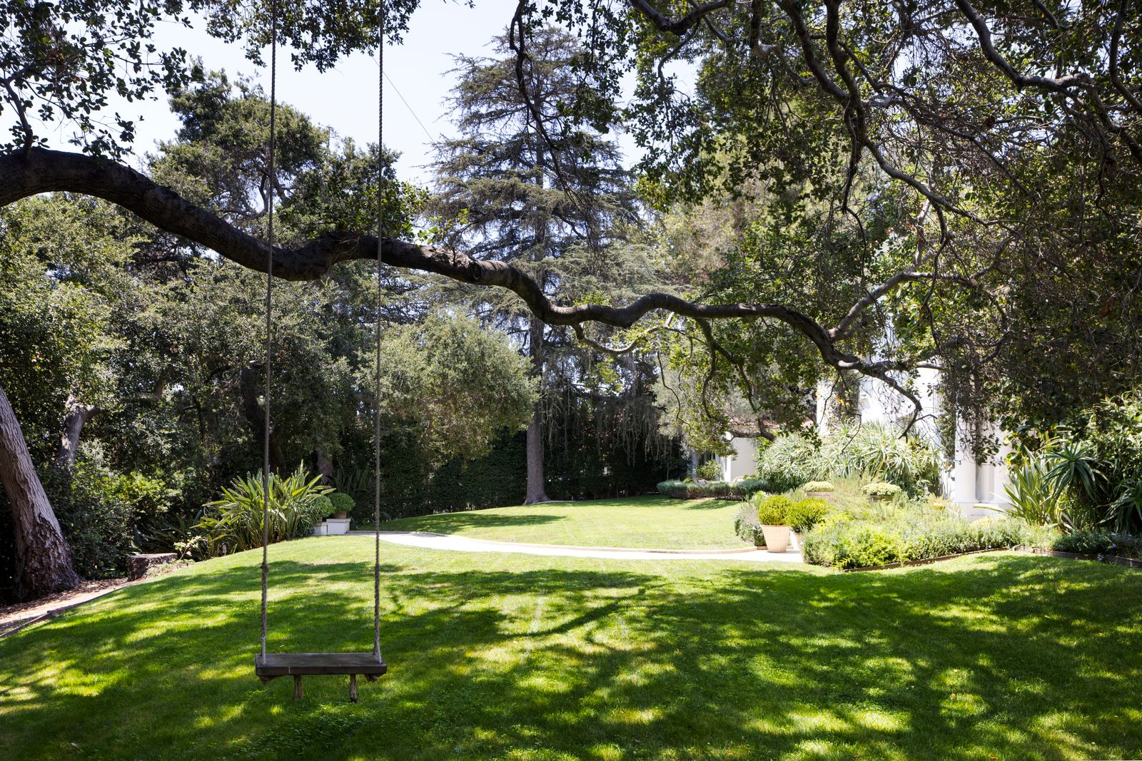 At the front of the property, a large tree anchors one of the estate’s most relaxed spots, where a suspended rope swing hangs above a broad grassy lawn. 