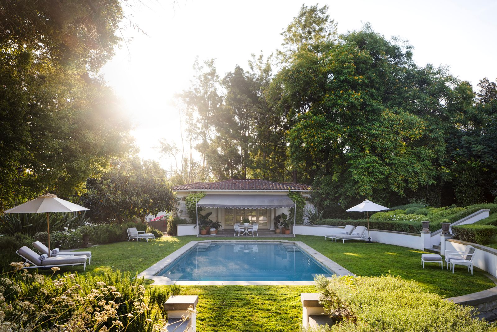 Heading down to the rectangular pool, stone pathways and trimmed hedges connect the terrace to surrounding gardens and lounge areas.