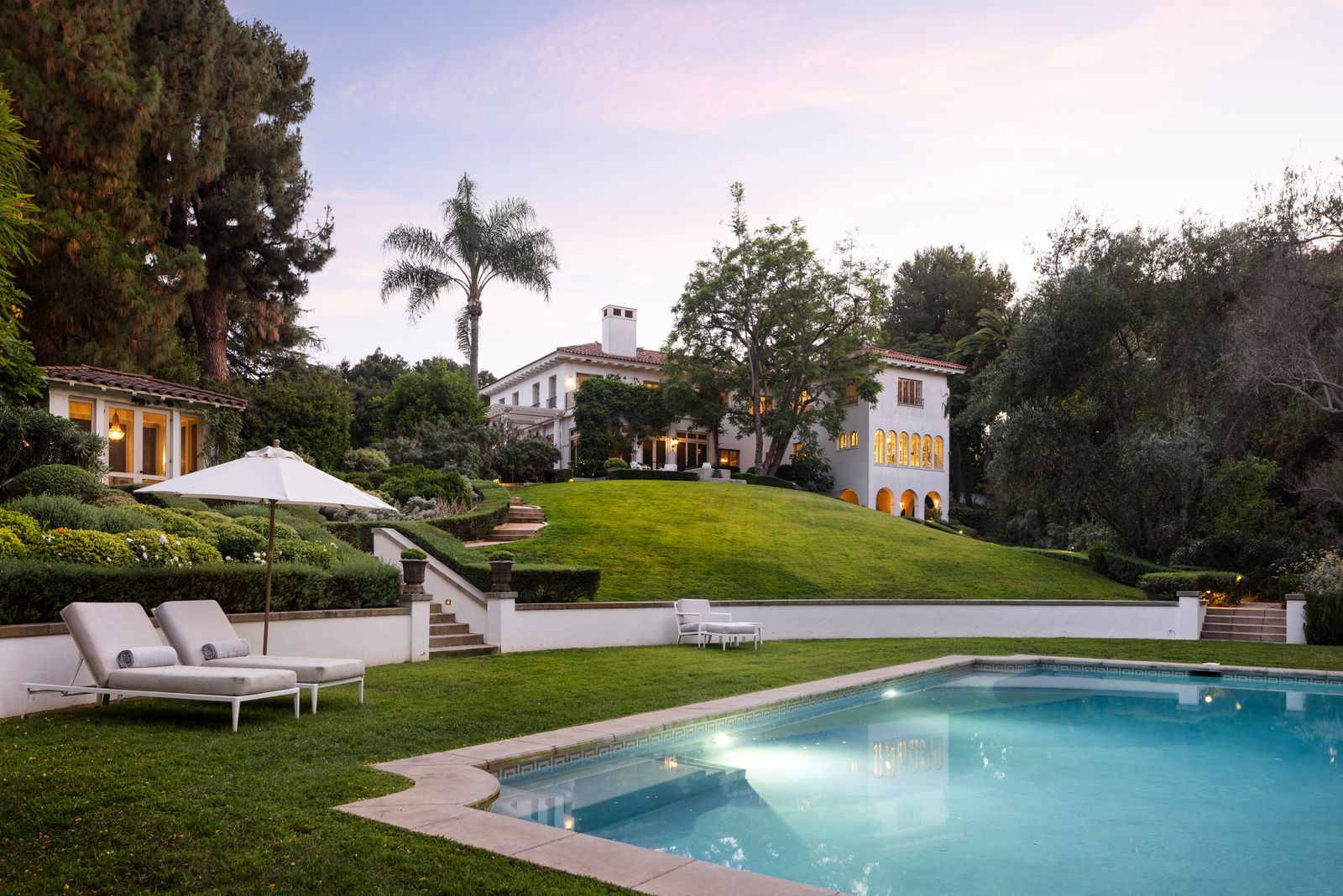 From the pool deck, the main residence stretches upward across the hillside, with arched windows, terraces, and ivy-covered walls overlooking the grounds below.