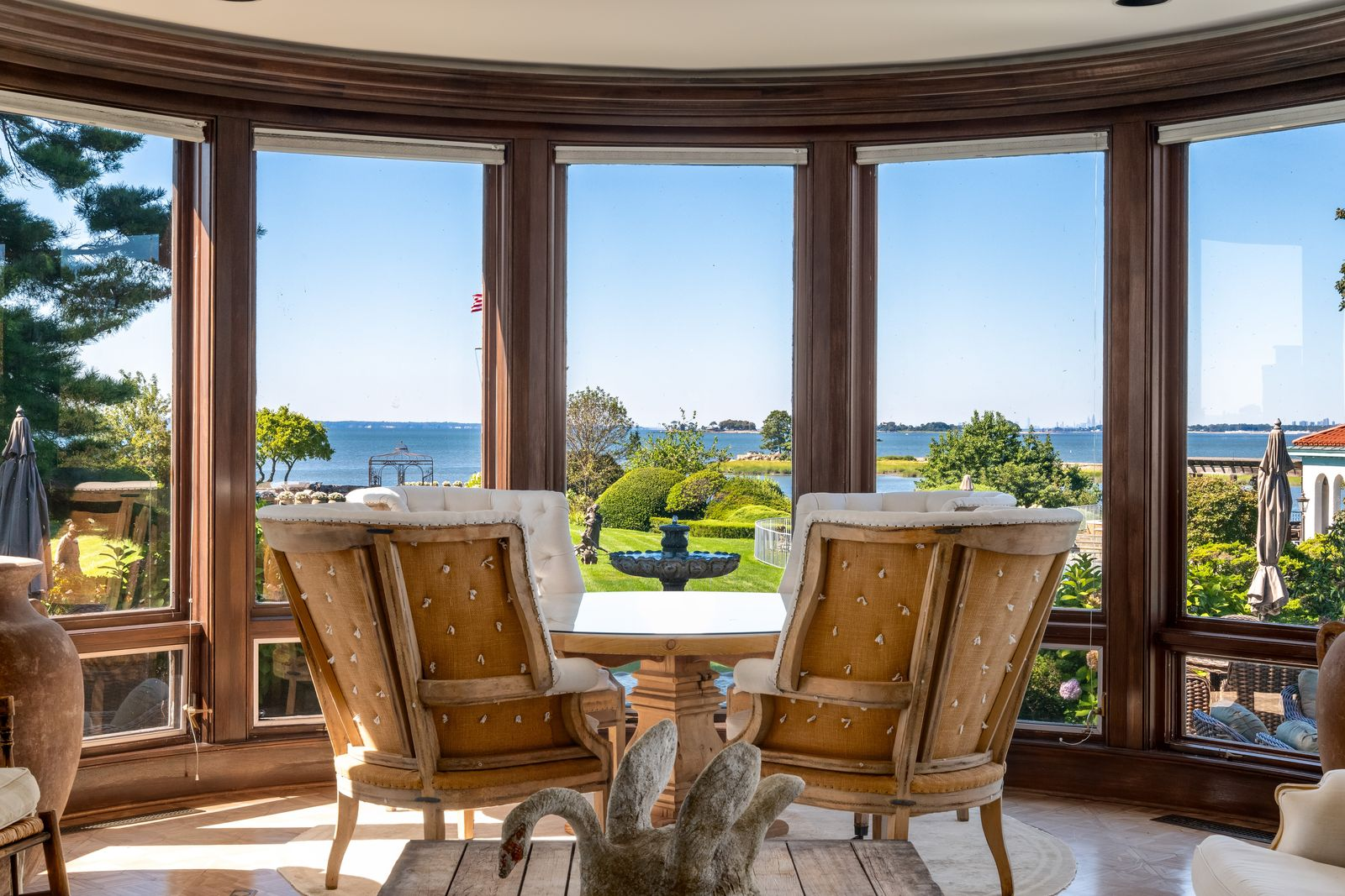 Oversized lounge chairs circling a round table are arranged directly in front of the windows, turning the space into a dedicated sitting area centered around the panoramic bay views.