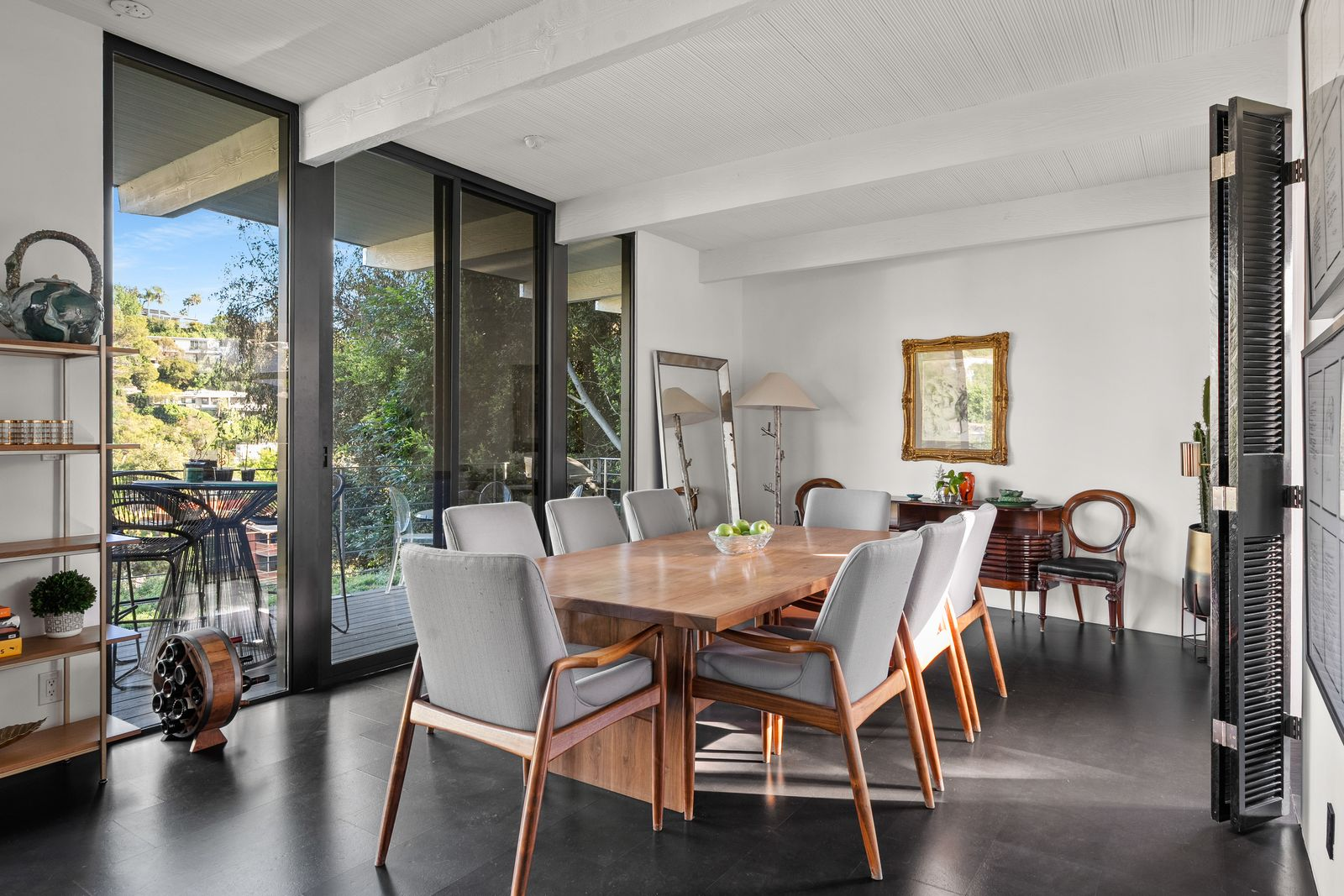 A few steps away, the dining room continues the home’s clean mid-century aesthetic with an understated layout centered around a long wood dining table and upholstered seating. 