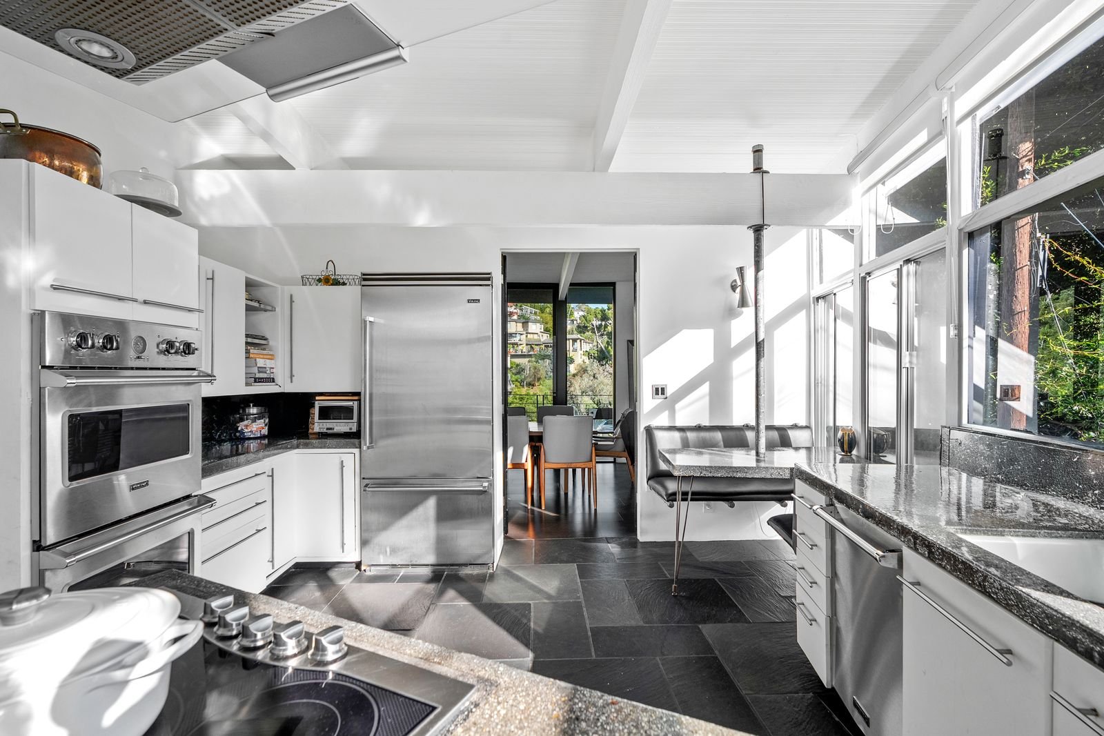Stainless steel appliances, integrated storage, and a compact breakfast nook introduce contemporary features without disrupting the restrained aesthetic that defines the rest of the home.
