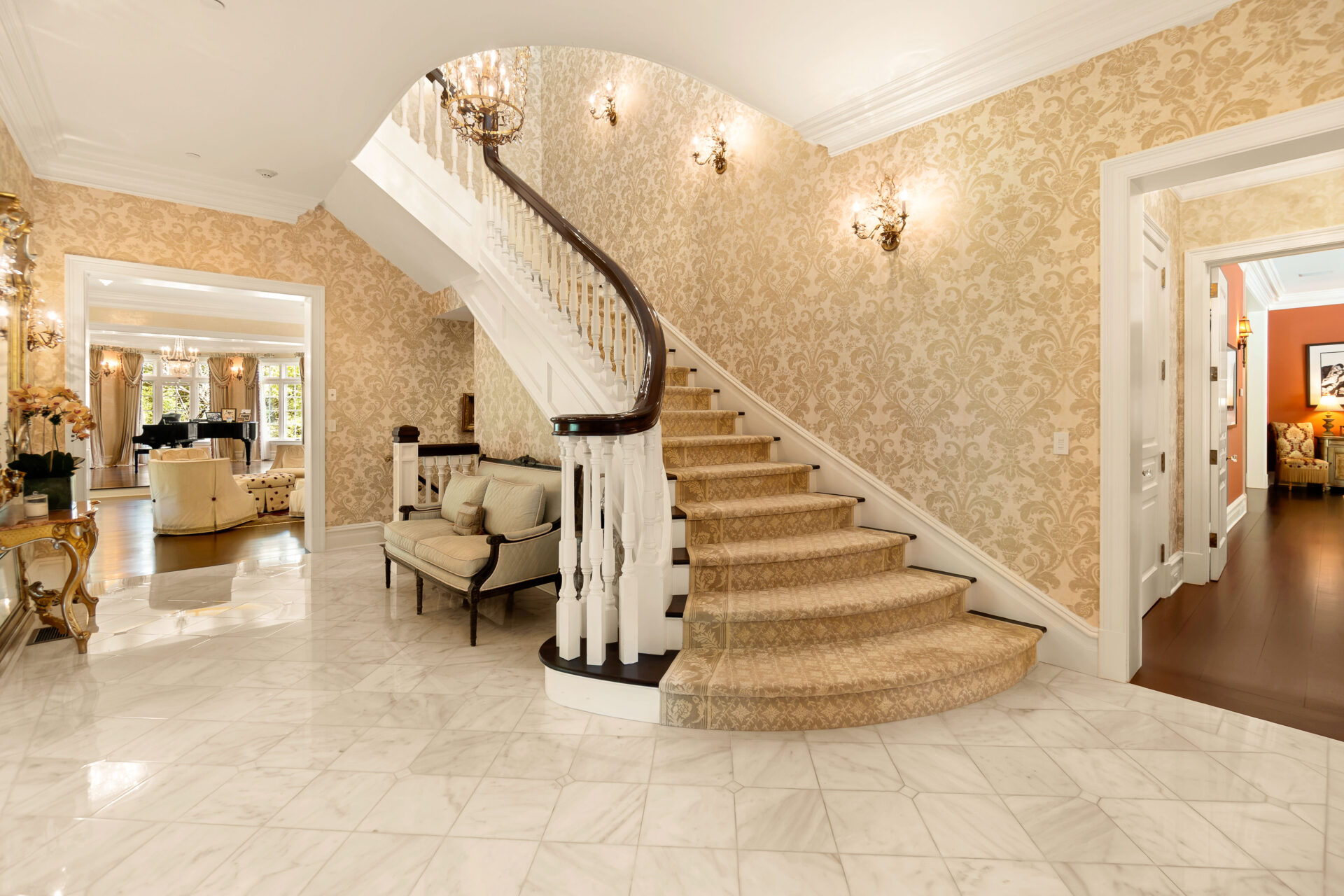 Polished marble floors extend throughout the space, while patterned wall coverings, decorative sconces, and crown molding reinforce the French-inspired design.