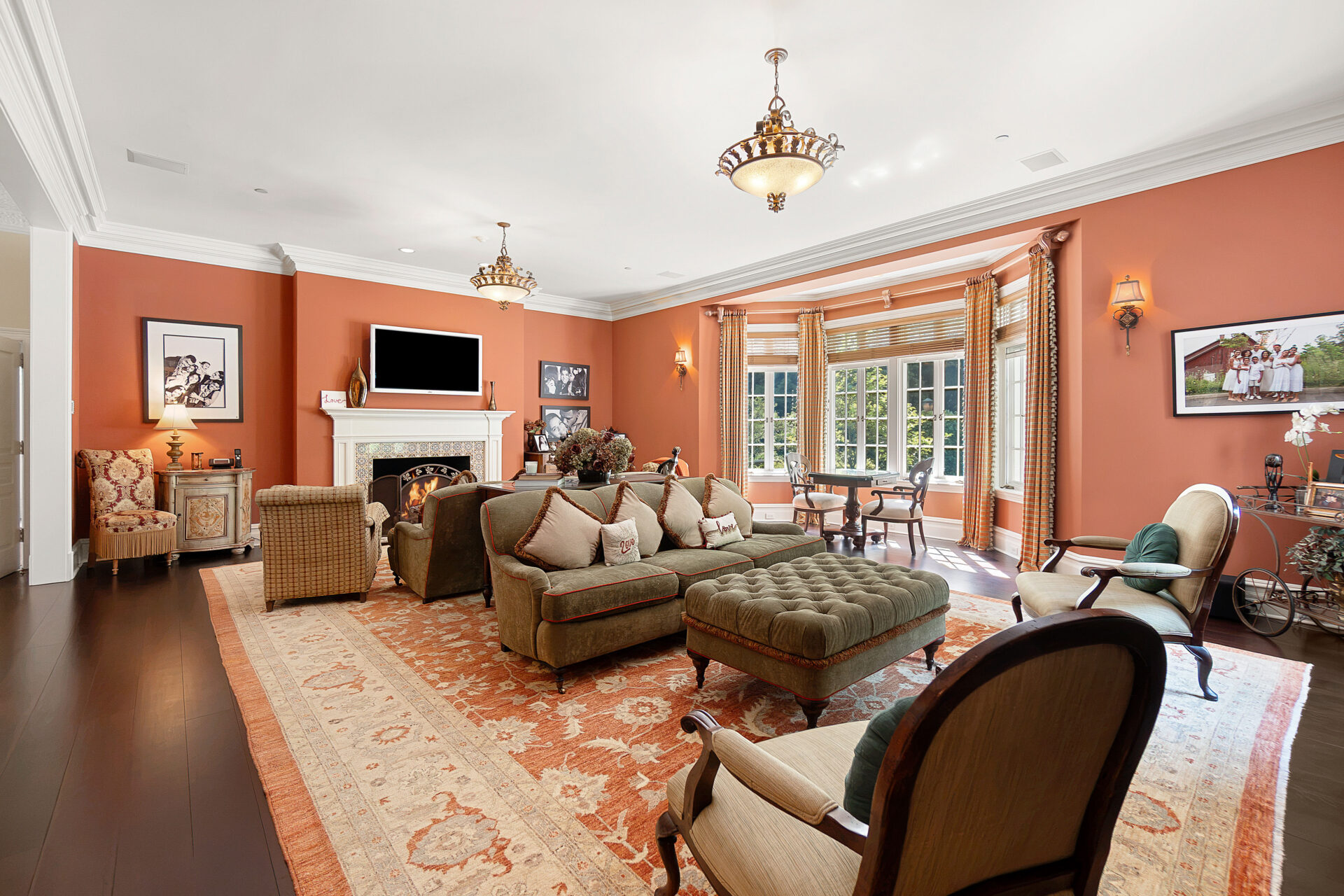 A large bay window anchors one end of the room, and at the opposite end, a fireplace with a carved mantel creates another seating area.