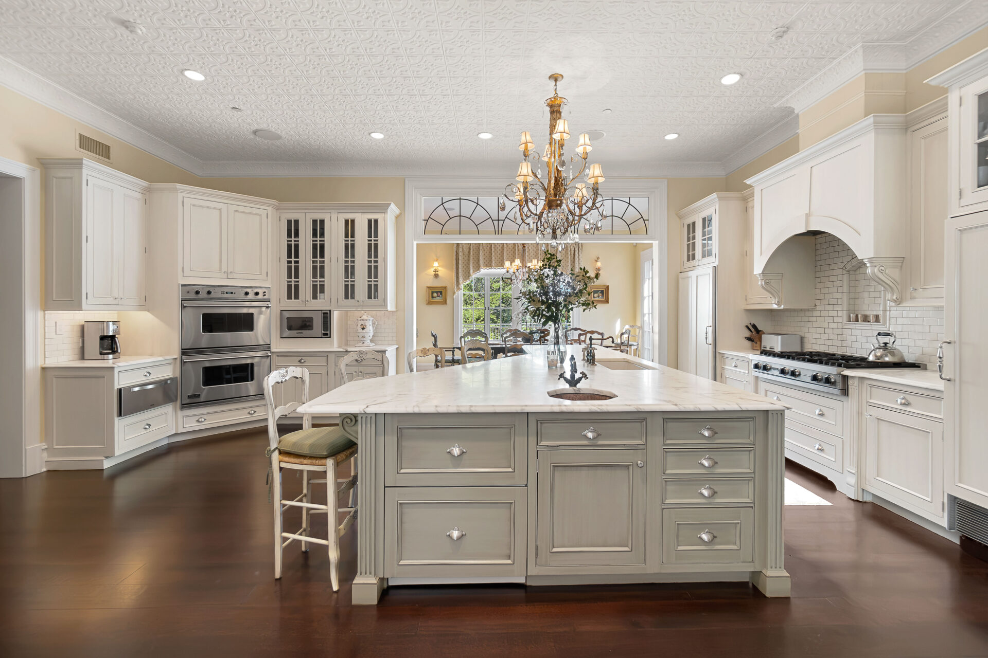 The kitchen is arranged around professional-grade appliances, extensive built-in storage, and long stretches of marble countertops. 