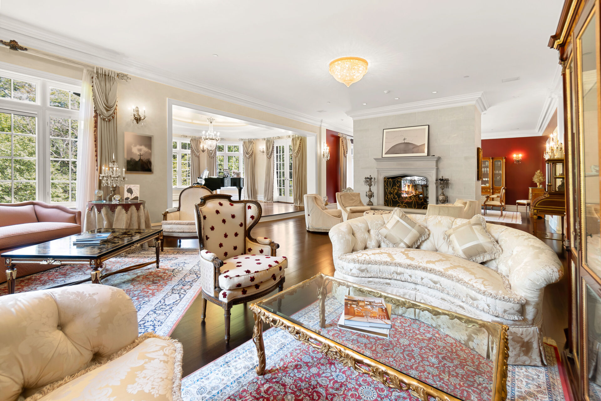 Seating groups are positioned atop patterned area rugs beneath crystal lighting, creating a space designed for conversation and entertaining.