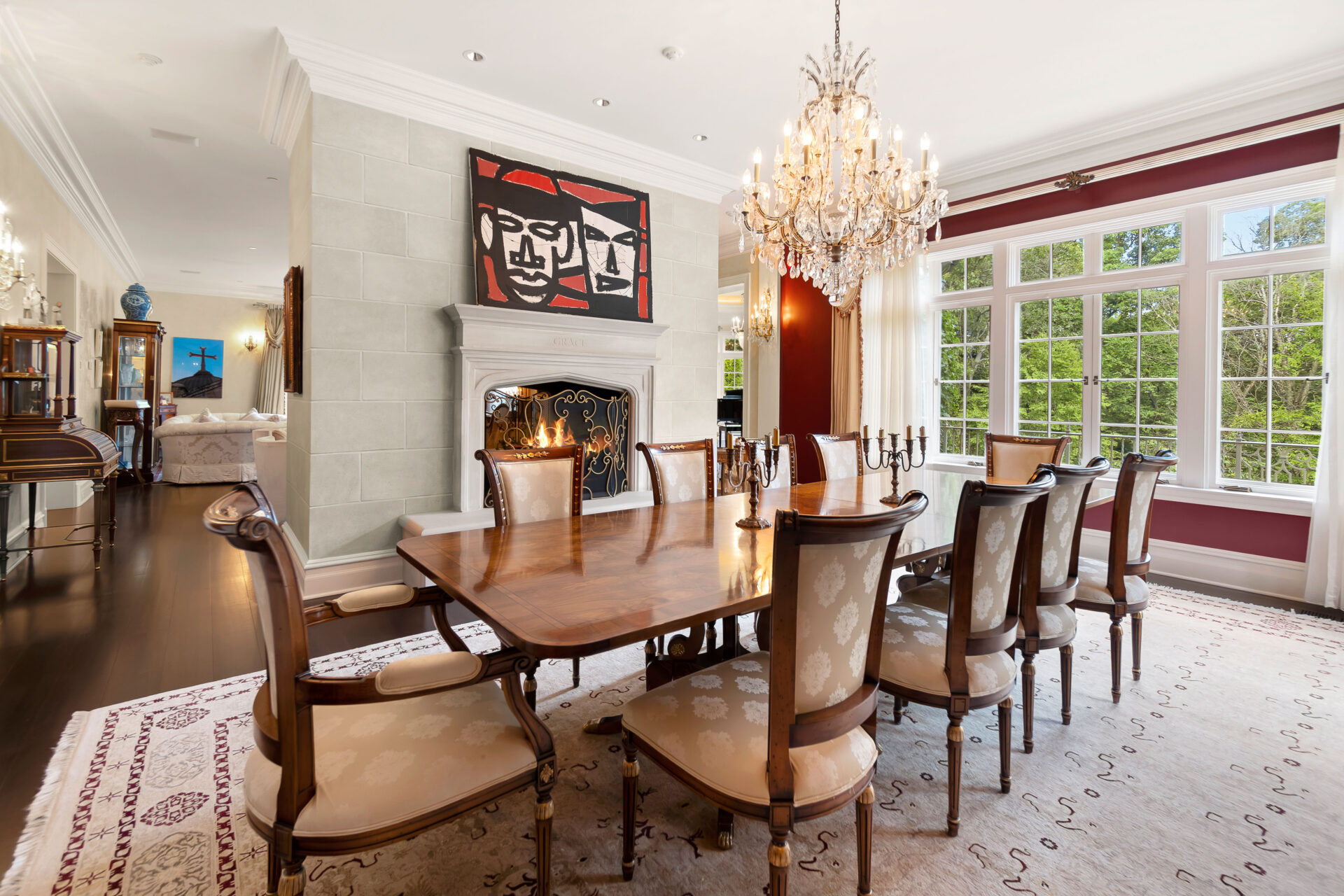 On the opposite side of the fireplace sits the formal dining room, where deep red walls and a large crystal chandelier create a more dramatic setting.