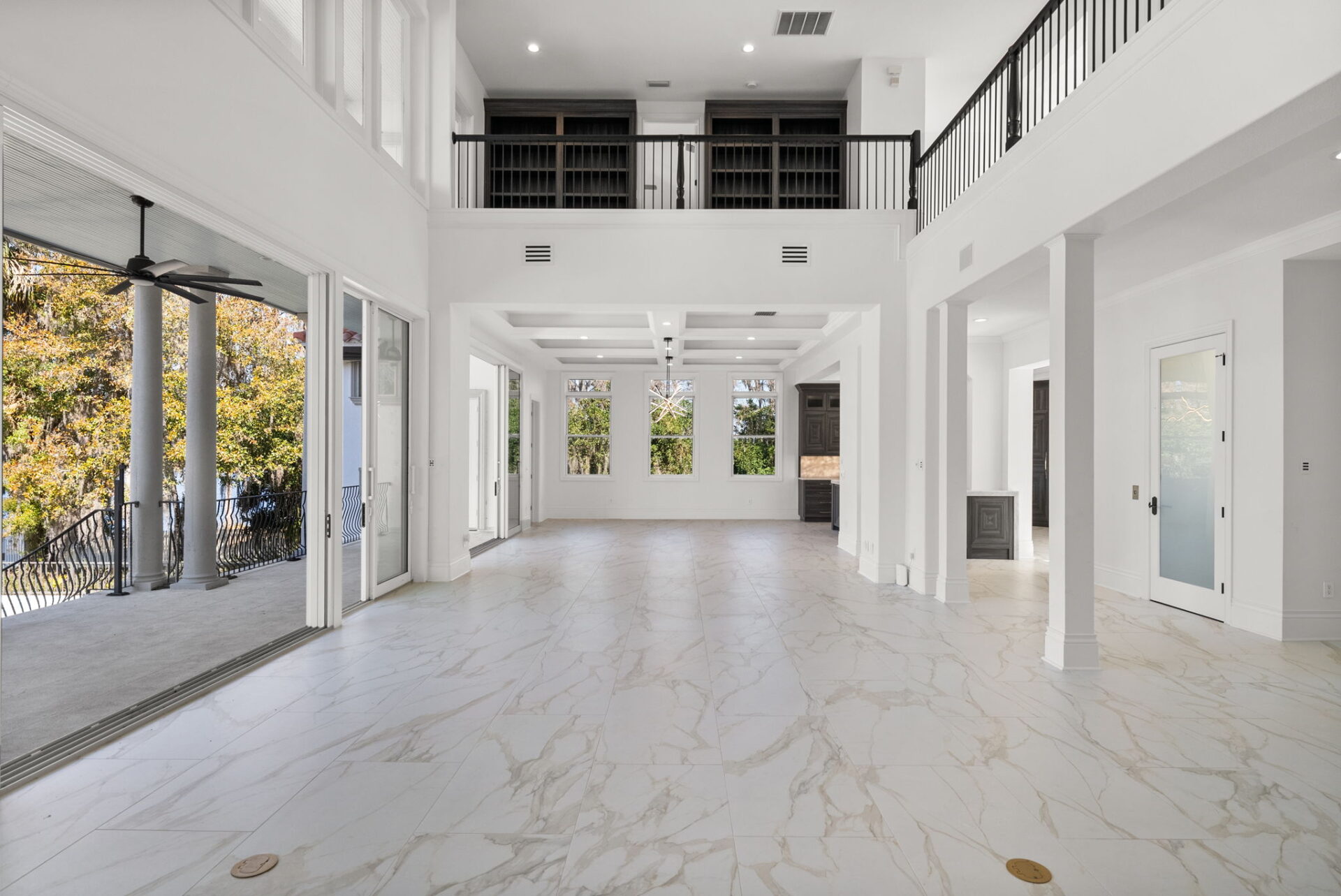 At the opposite end, the open layout transitions into a dedicated dining area positioned beneath a pair of contemporary chandeliers.