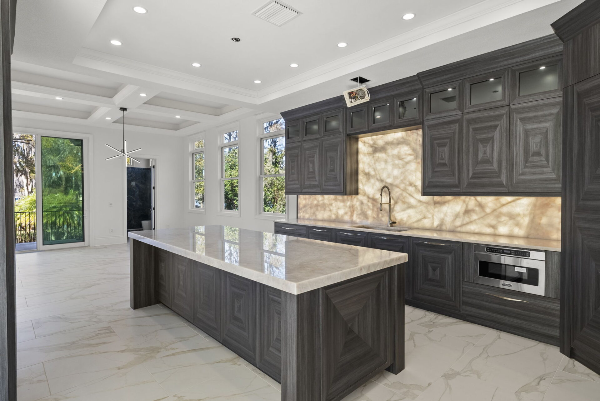 Directly next to the dining area, the kitchen's contemporary aesthetic starts with a massive waterfall-edge island in the center of the room.