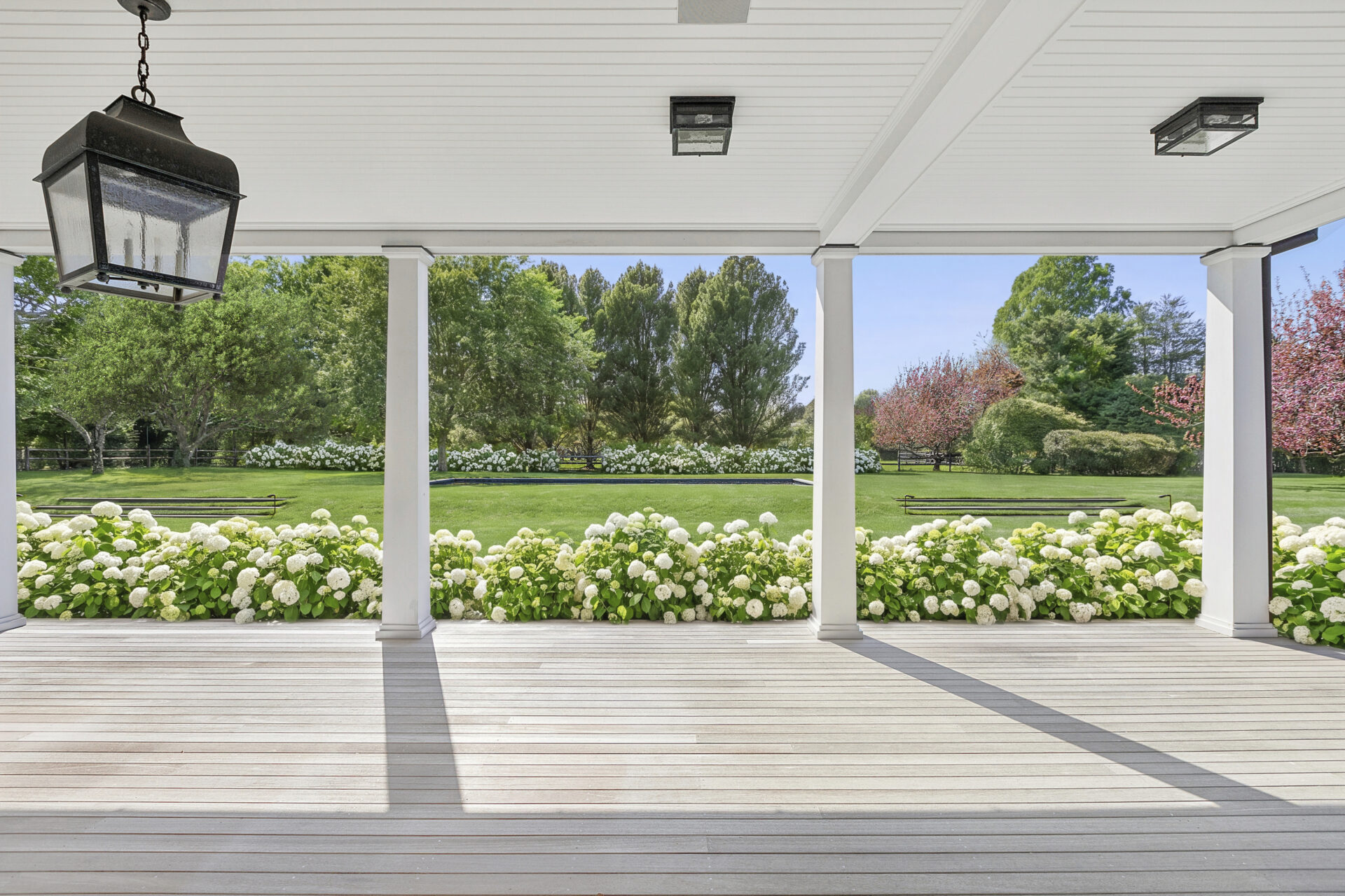 The porch stretches almost the entire length of the home, providing room for multiple seating and dining arrangements beneath the shelter of the overhang.