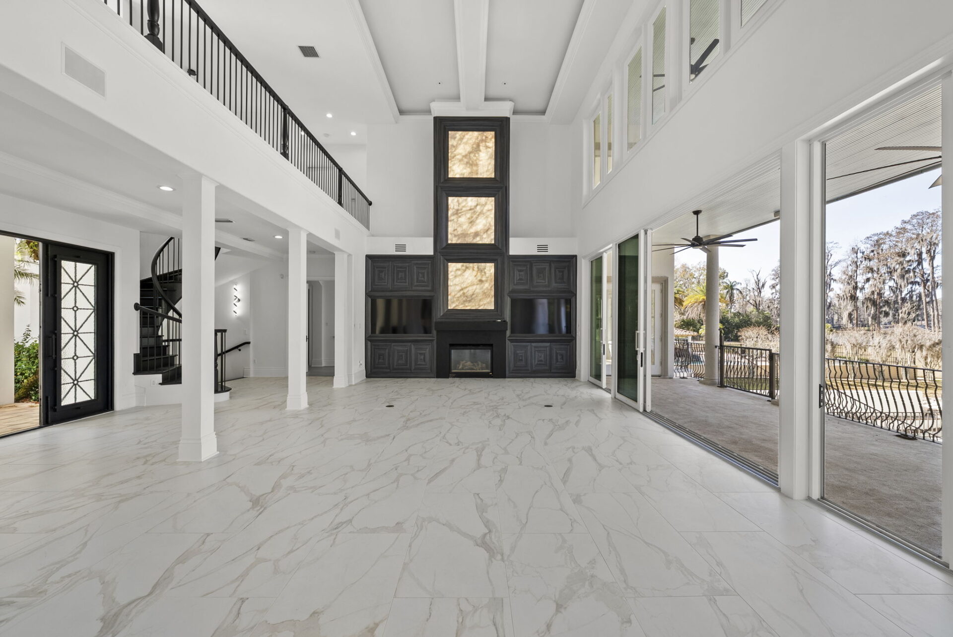 At one end of the room is a custom-built media wall finished in dark wood, incorporating a fireplace, integrated shelving, and dual television niches framing illuminated stone accents.