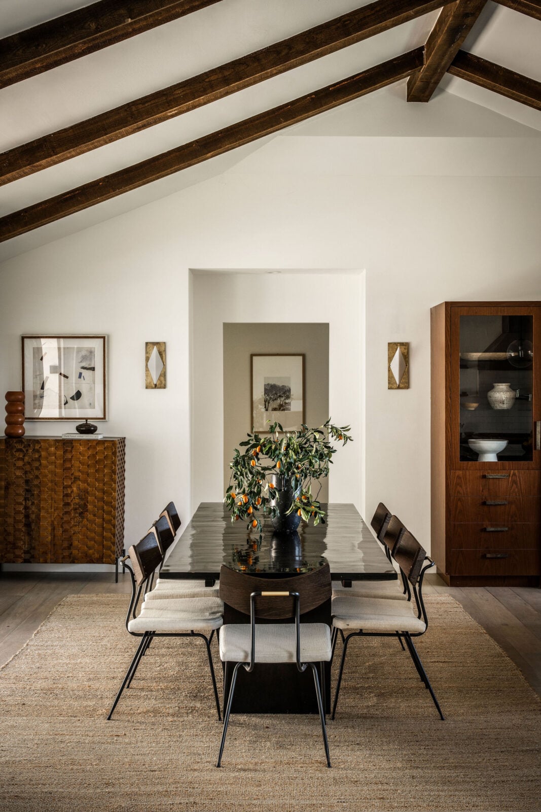 Positioned just around the corner from the living room, the dining area continues the home's open-concept layout beneath the vaulted ceiling and exposed wood beams.