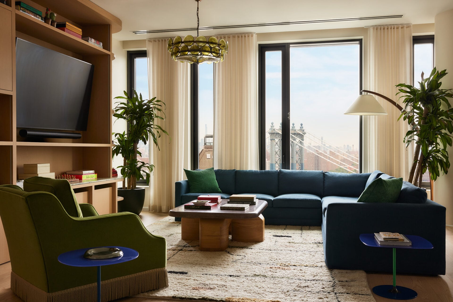 A deep blue sectional lines the seating area atop a textured rug, while custom white oak built-ins provide space for books, artwork, and display pieces.