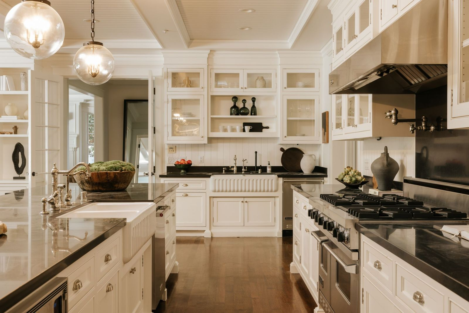 Custom cabinetry stretches from floor to ceiling, incorporating glass-front display cabinets, open shelving, and extensive storage. 