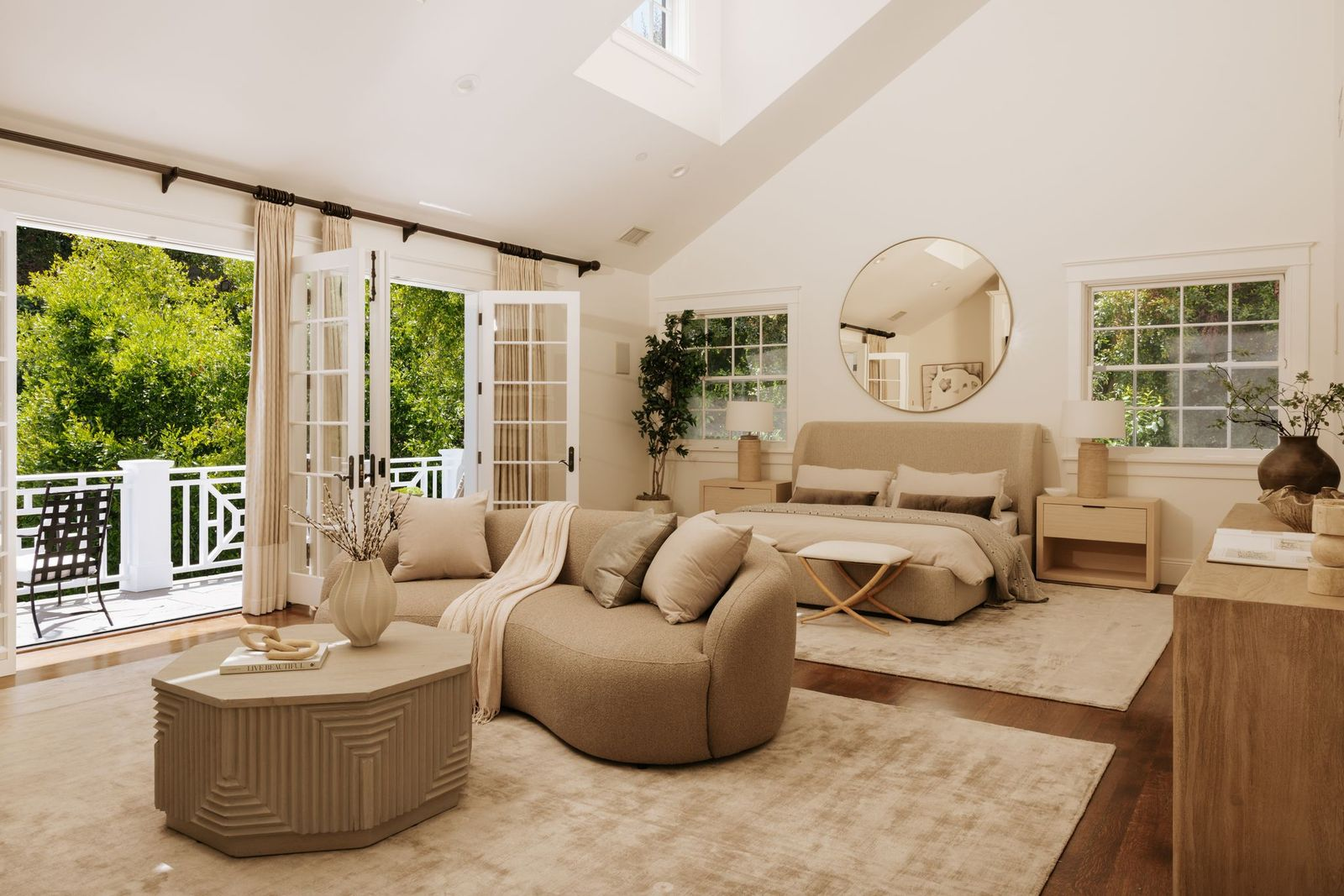 In the bedroom, vaulted ceilings and a skylight bring additional natural light into the room, while French doors open to a private balcony overlooking the landscaped grounds. 
