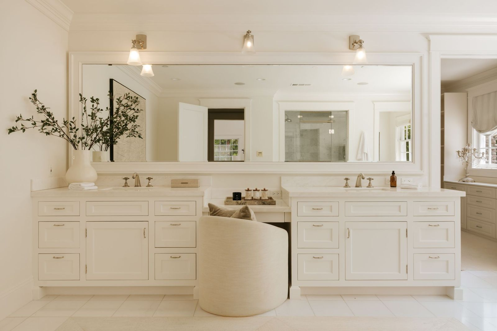 The adjoining bathroom features dual vanities separated by a dedicated makeup station and an oversized mirror that spans the length of the room. 