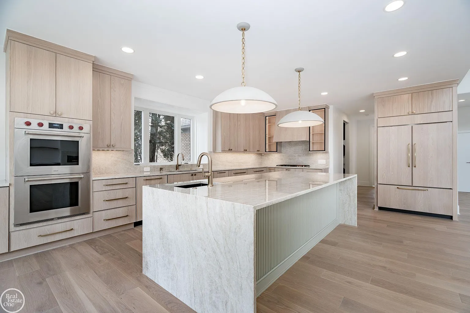 Professional-grade Wolf and Sub-Zero appliances are incorporated throughout the layout, including double wall ovens, a gas cooktop, and refrigeration concealed within the custom cabinetry. 