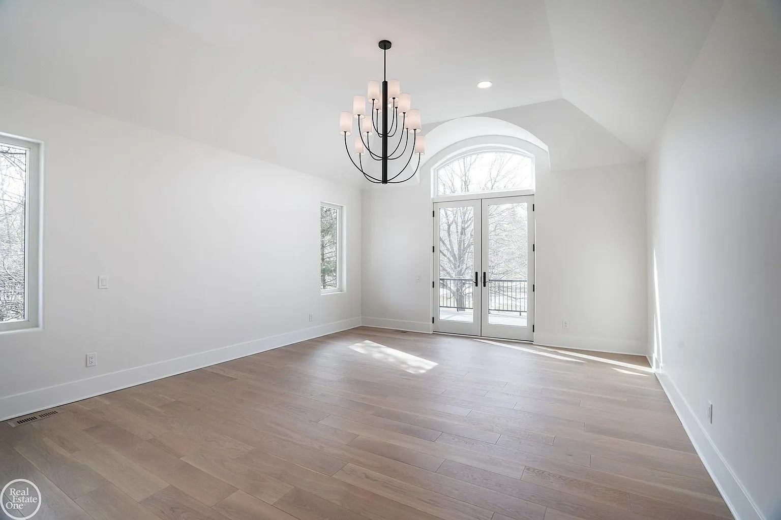 Entering the suite, the bedroom features vaulted ceilings, oversized windows, and French doors that open directly onto a private deck. 