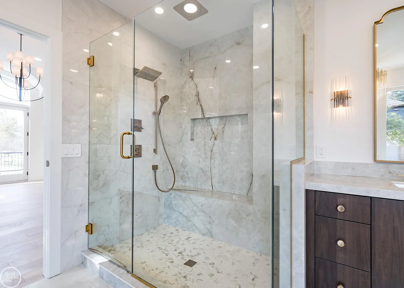 A glass-enclosed shower features full-height stone walls, built-in bench seating, and multiple shower fixtures.