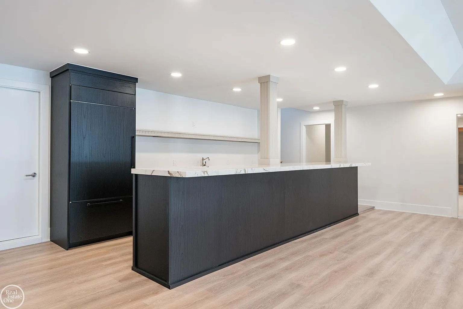A full wet bar with dark cabinetry and bright stone countertops. 