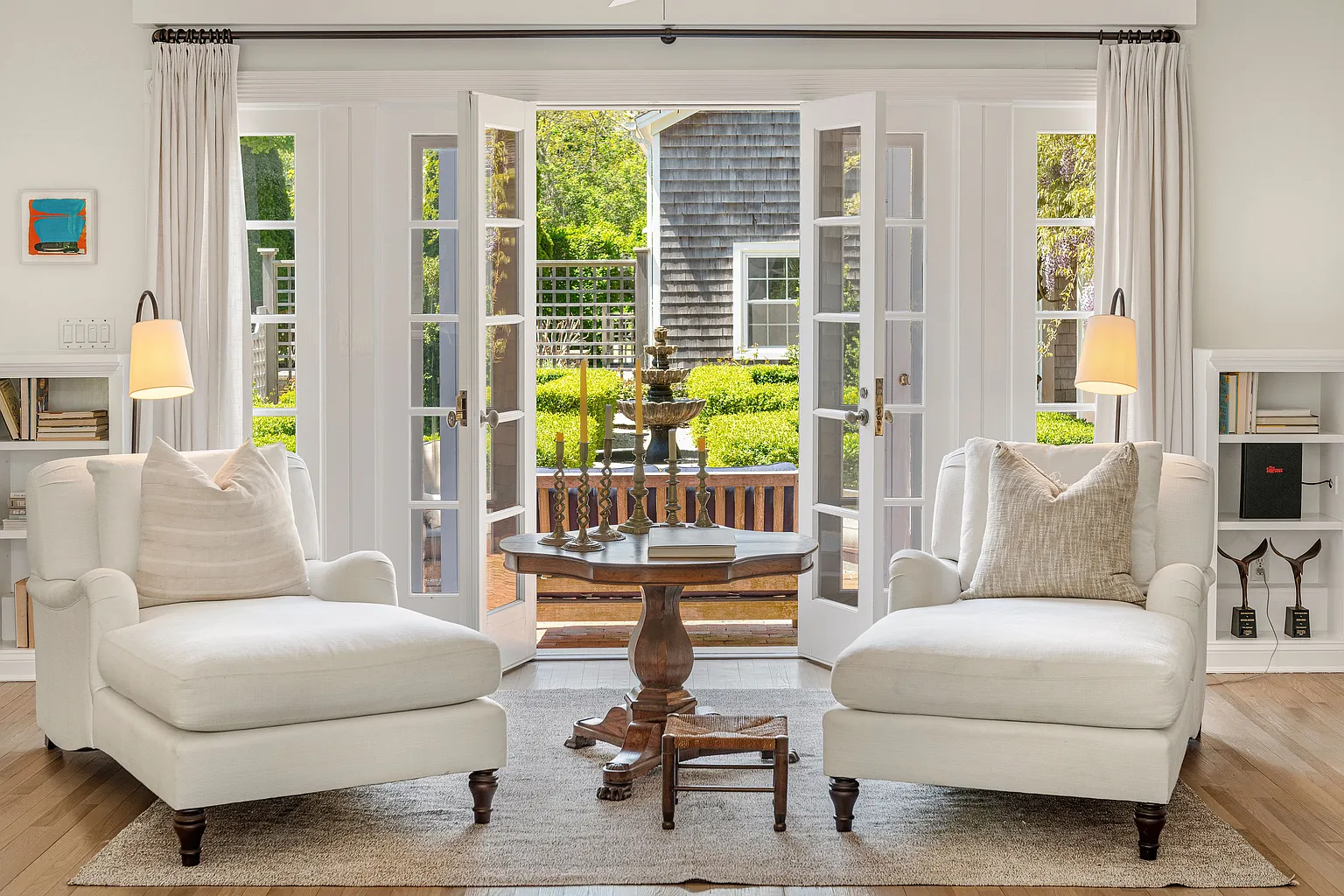 Across the room, a second sitting area is positioned beside large French doors and windows overlooking the property's gardens and orchards. 