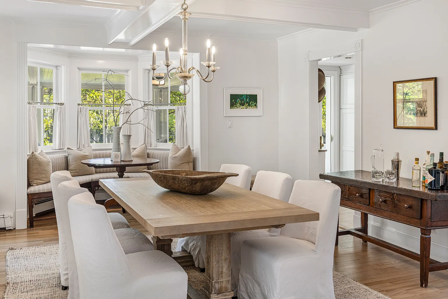 The dining area begins with a wood dining table positioned beneath a traditional chandelier.