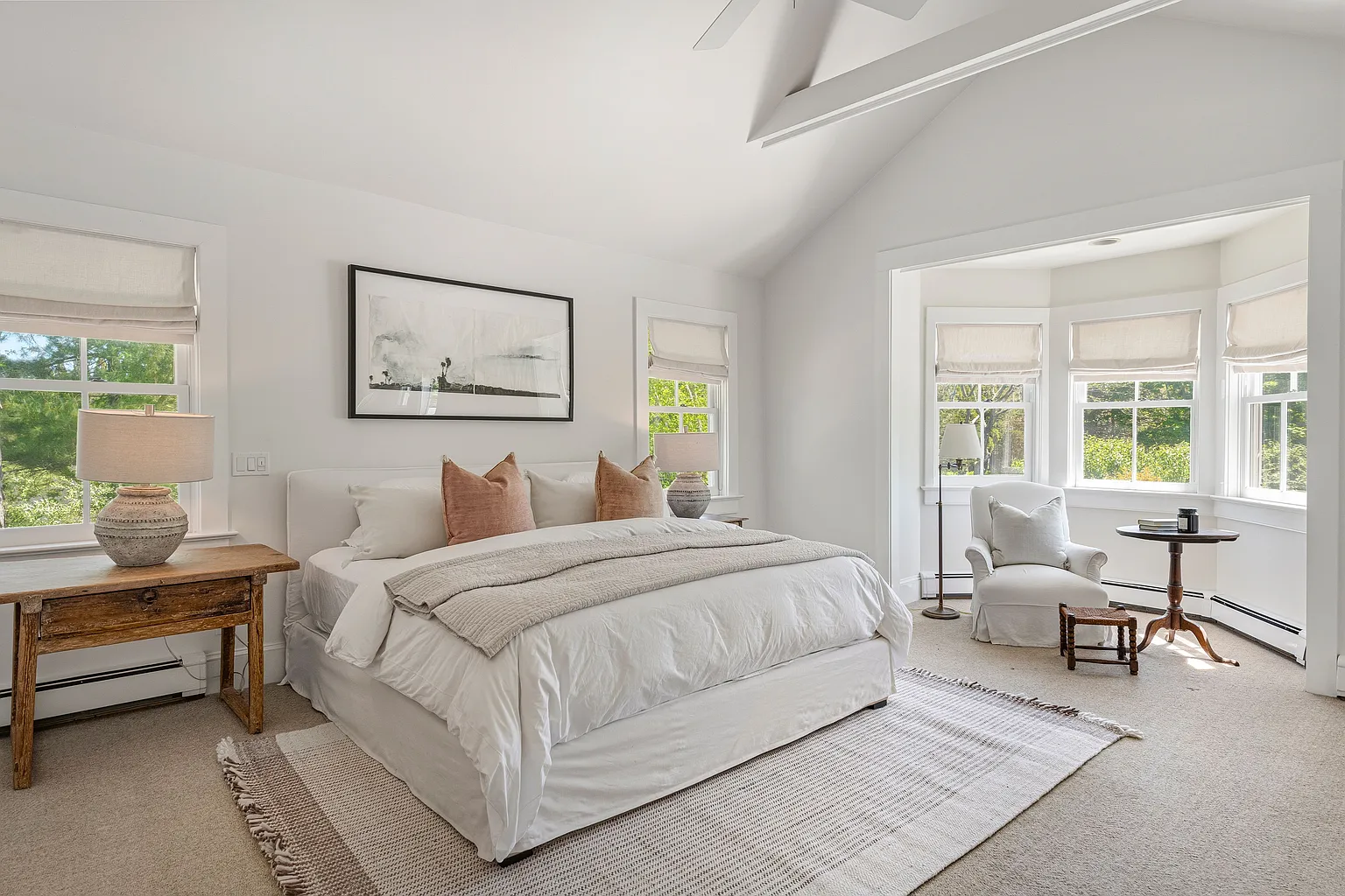 The bedroom starts the suite off with soft neutral finishes lining the bed next to a small curved alcove set up as a reading nook.