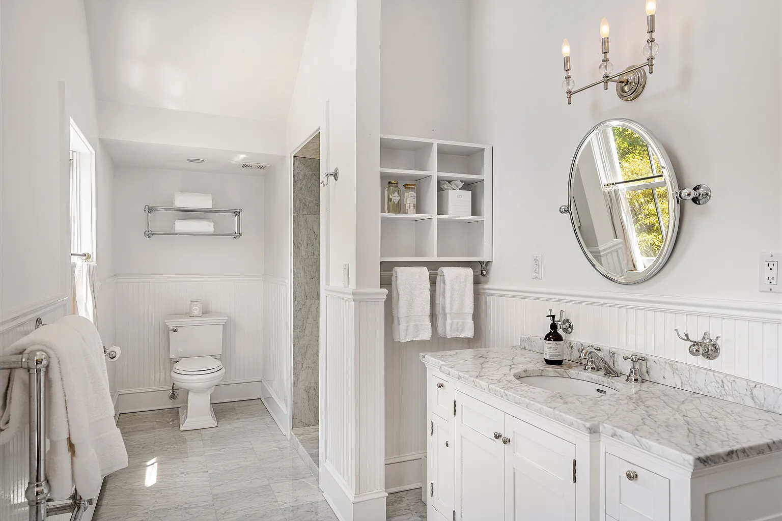 The en-suite bathroom continues the home's classic design with white millwork, marble surfaces, and traditional fixtures. 