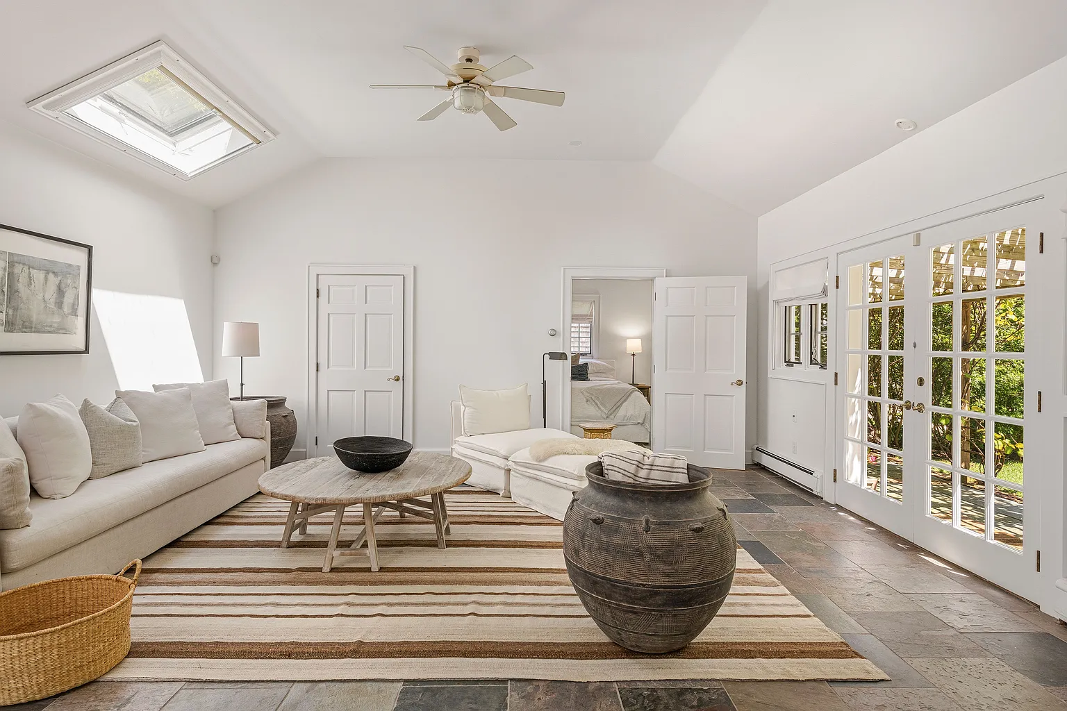 The structure features its own living area beneath vaulted ceilings, with French doors opening directly to the surrounding gardens and pool terrace.