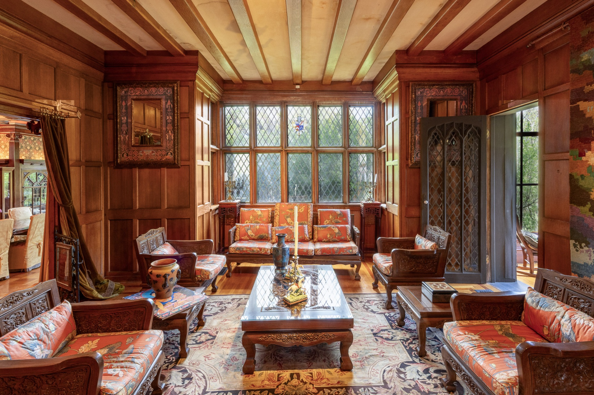 The first of the two main living rooms serves as a formal sitting room, centered around a wall of diamond-pane leaded glass windows that draw natural light into the richly detailed interior. 