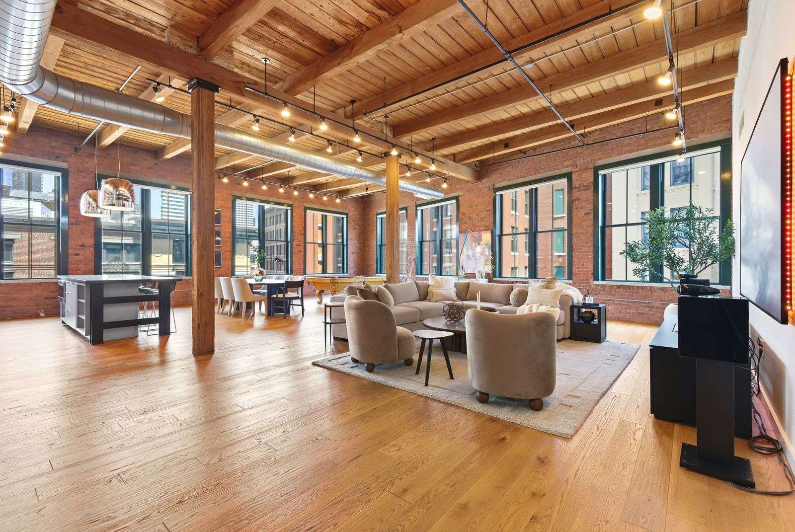 Within the space, exposed ceiling beams add a subtle industrial edge, while warm lighting and brick-lined walls soften the look.