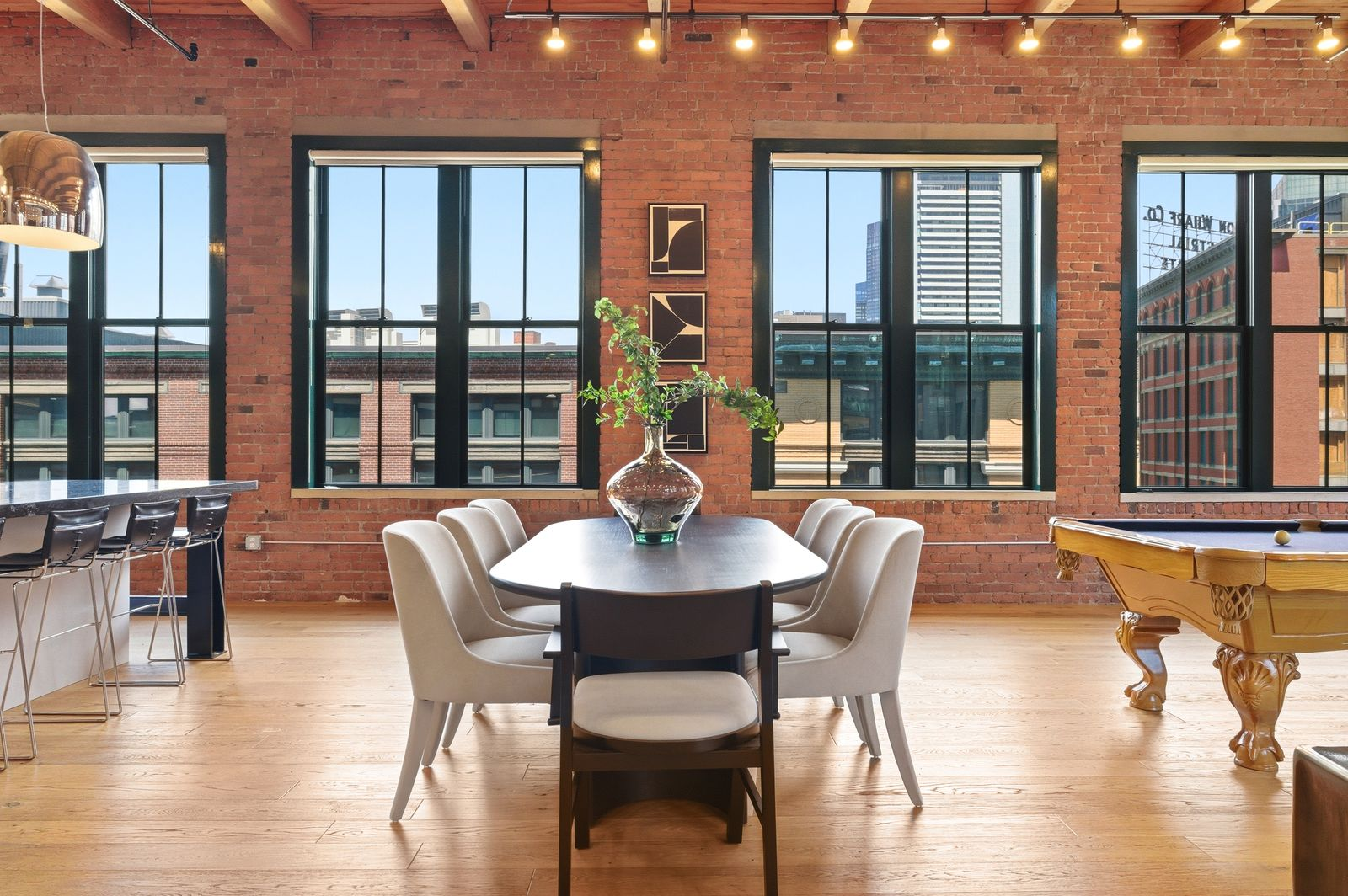 Next up is the dining area, which features a dark wood dining table with seating for eight, sitting against a backdrop of exposed brick walls and Boston views.