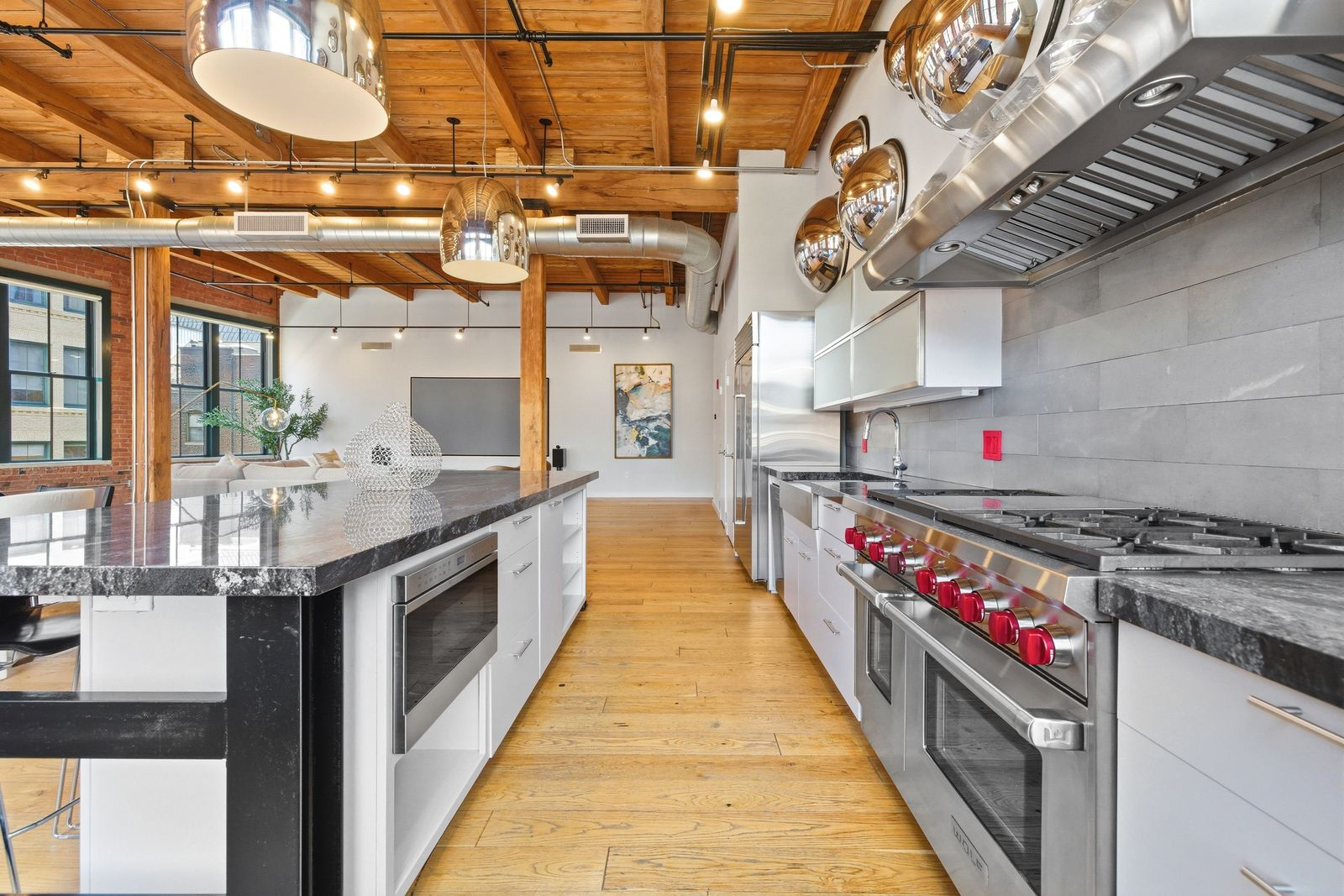Premium stainless-steel appliances include a professional-grade Wolf range with double ovens, a commercial-style vent hood, and an oversized refrigerator.