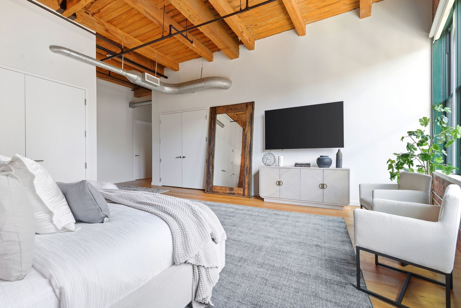 Light-toned flooring and neutral furnishings help soften the brick and wood elements, while the room's open layout makes it feel spacious.