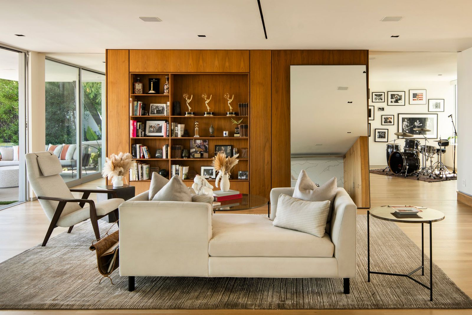 A custom wall of warm wood cabinetry lined with built-in shelving, which is used to display books, framed photographs, and personal memorabilia.