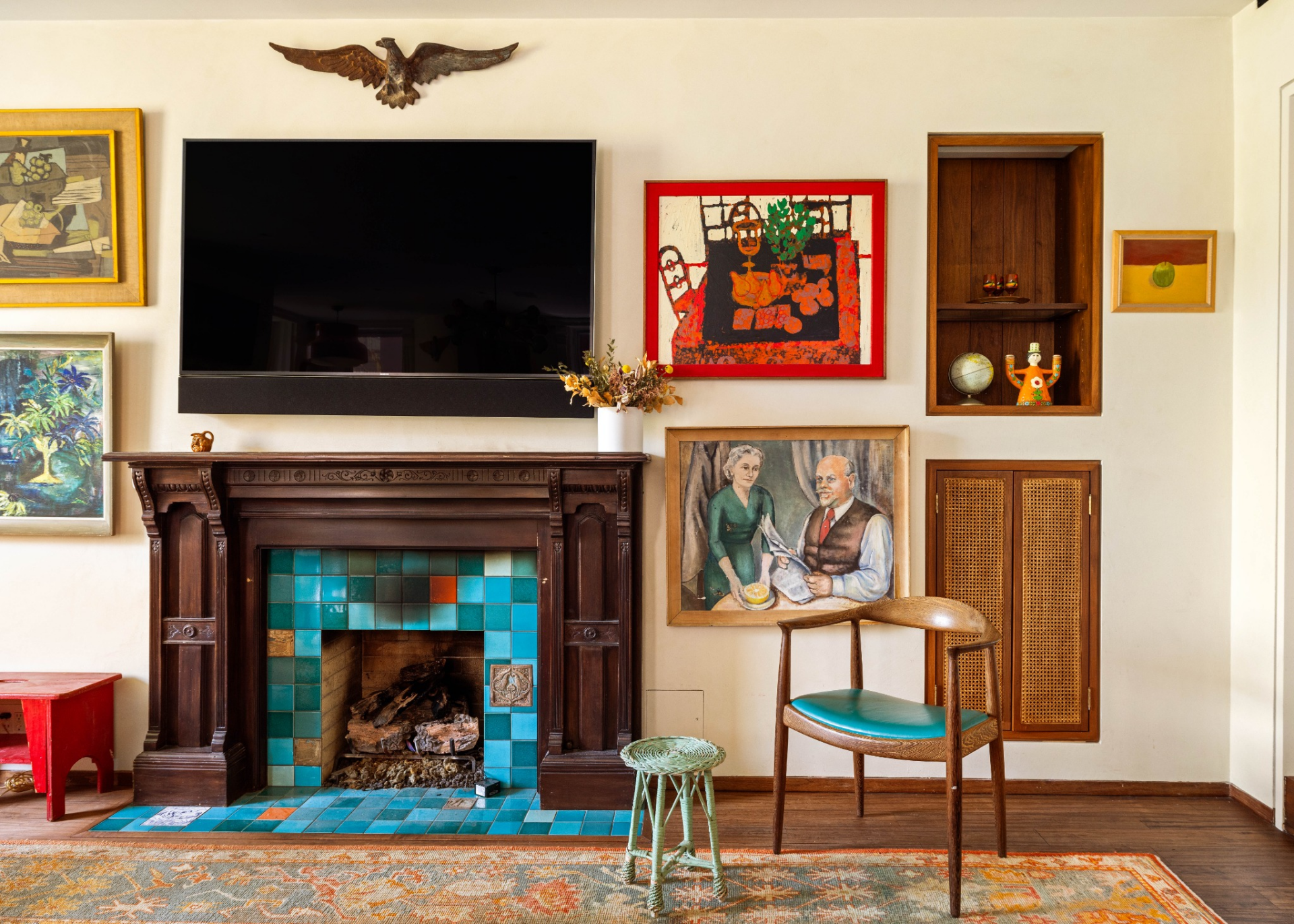 Beyond the kitchen, a sitting area centered around a dark wood fireplace with vibrant turquoise tilework creates a natural gathering spot.