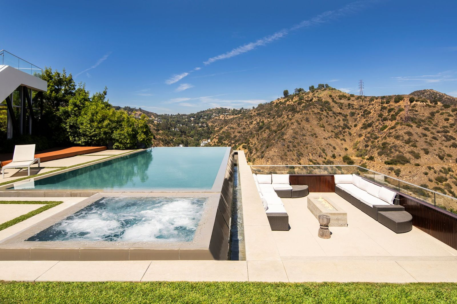 The focal point is a large infinity-edge pool and spa, separated by a sleek overflow edge that sends water cascading into the basin below.