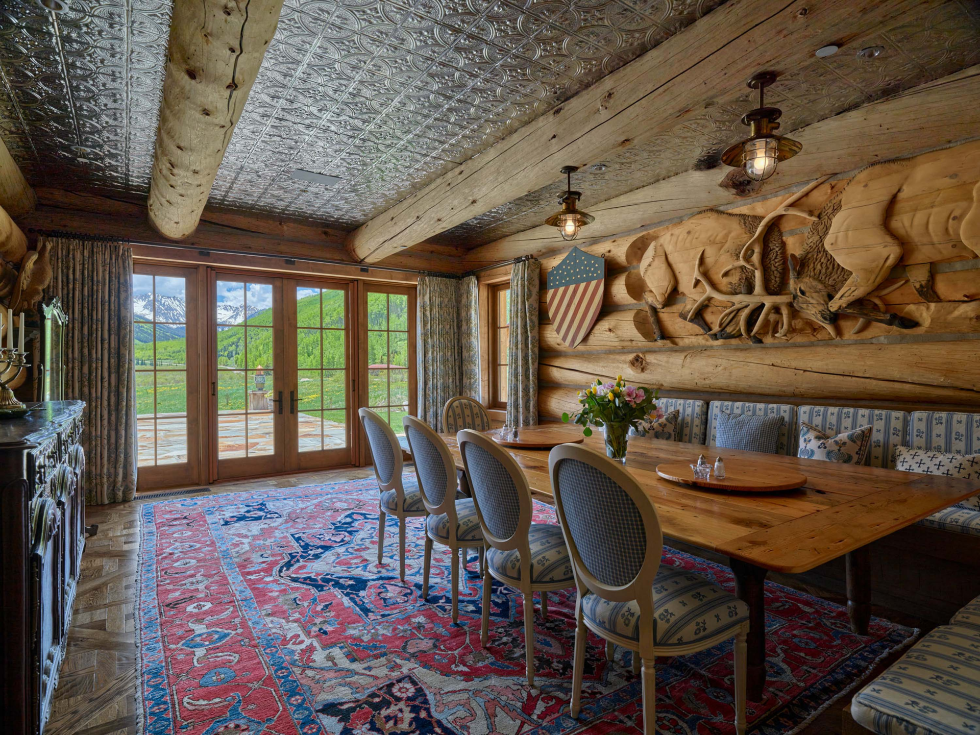 Built-in banquette seating wraps around a wood table, creating a comfortable breakfast-room setting tucked within the log structure.