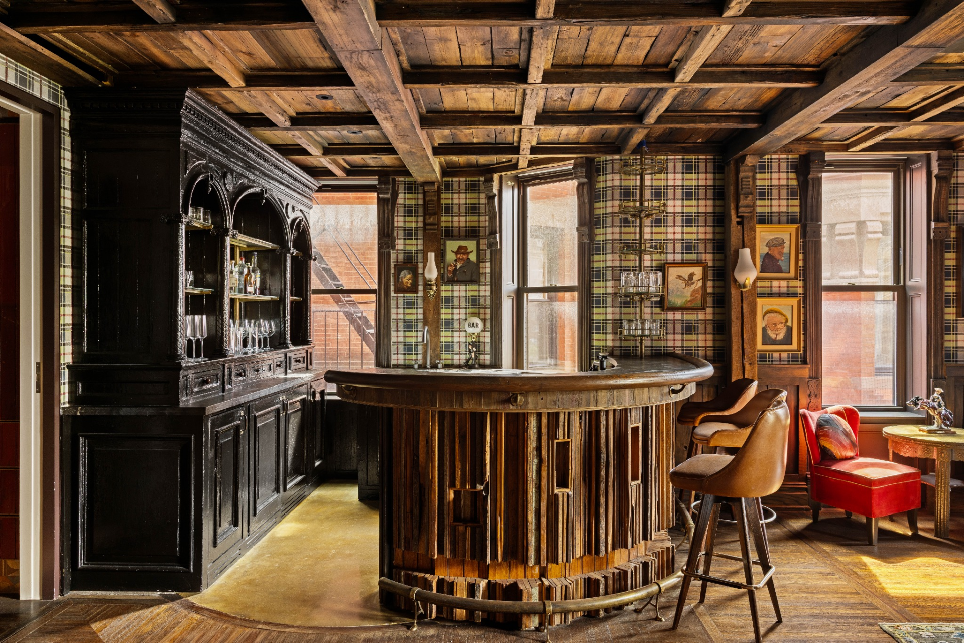 At the center of the space is a custom-built bar wrapped in wood and paired with a dramatic back bar framed by jewel-toned stained glass panels.